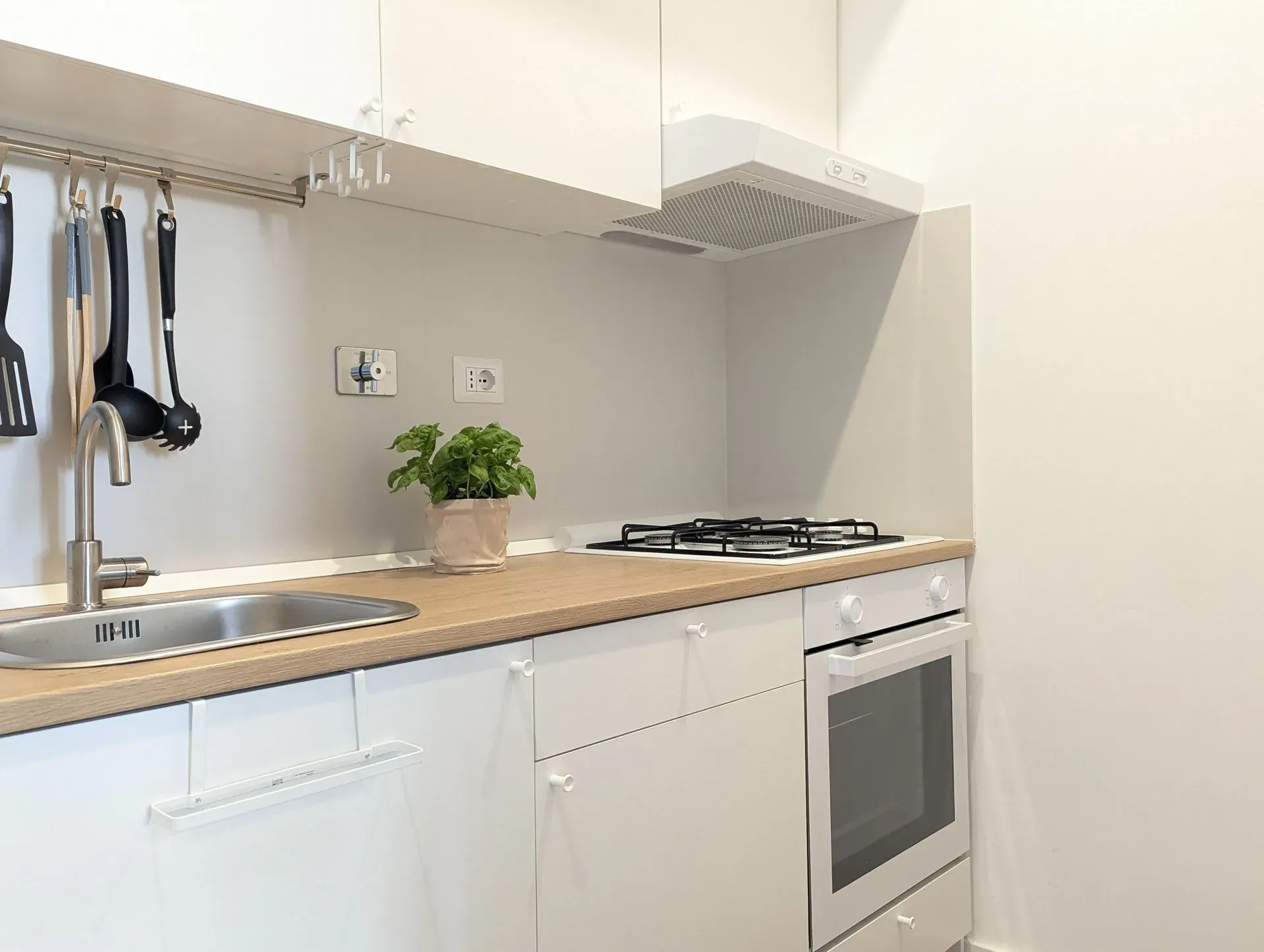 Cucina bianca con forno, piano cottura e utensili
