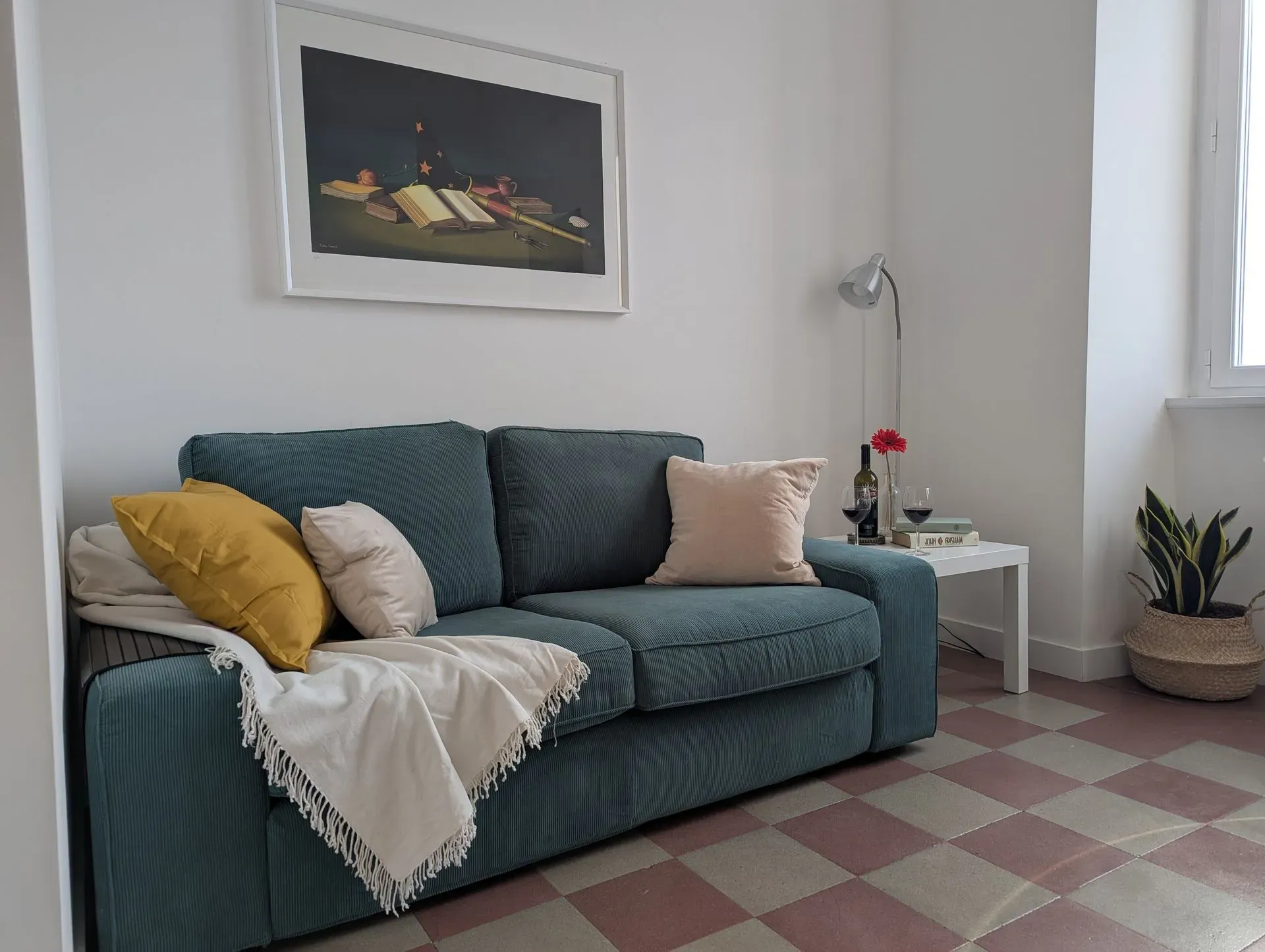 Divano azzurro con cuscini e plaid accanto alla finestra